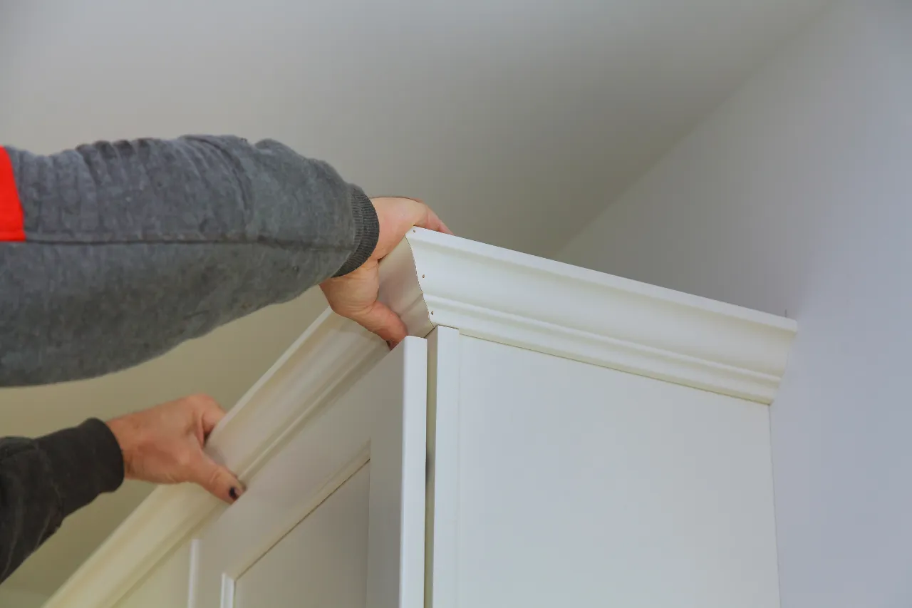 Hands installing white cabinet trim in a New Jersey home