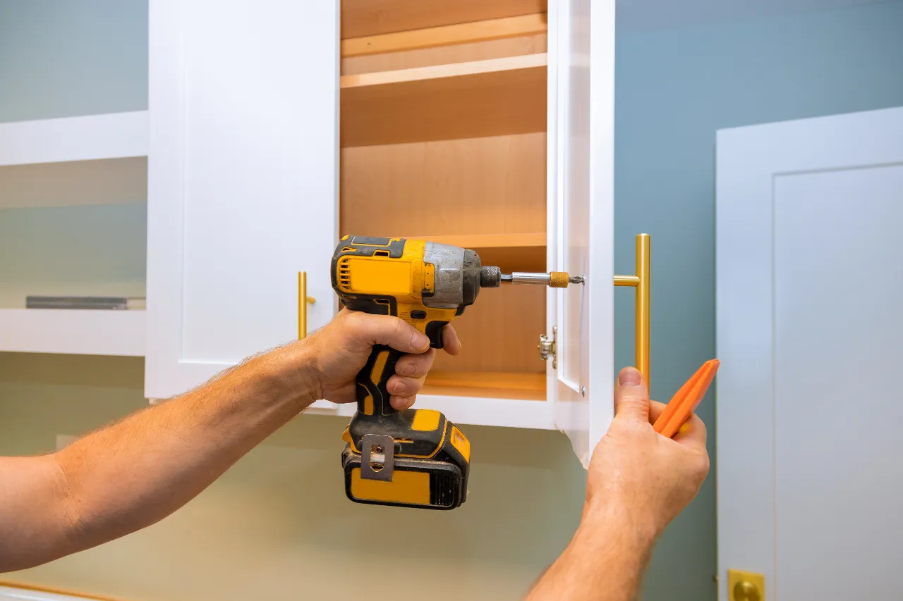 Installing modern golden handles on white kitchen cabinets