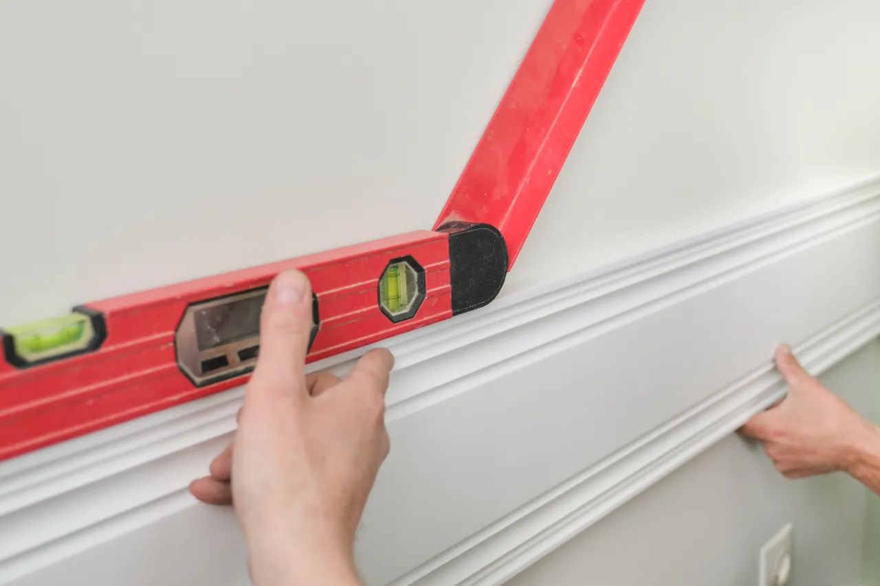 Level tool on wall during crown molding installation in New Jersey