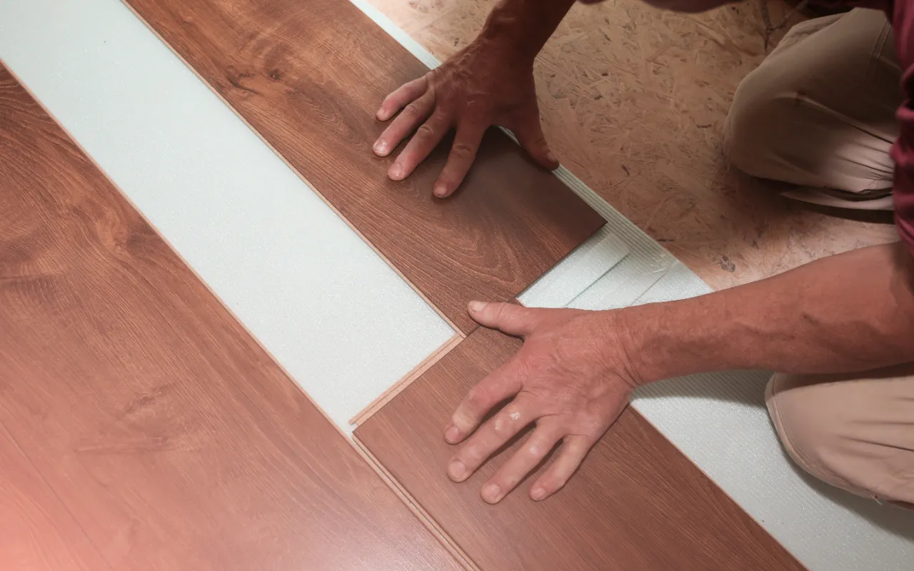 Worker installing laminate flooring in a New Jersey apartment