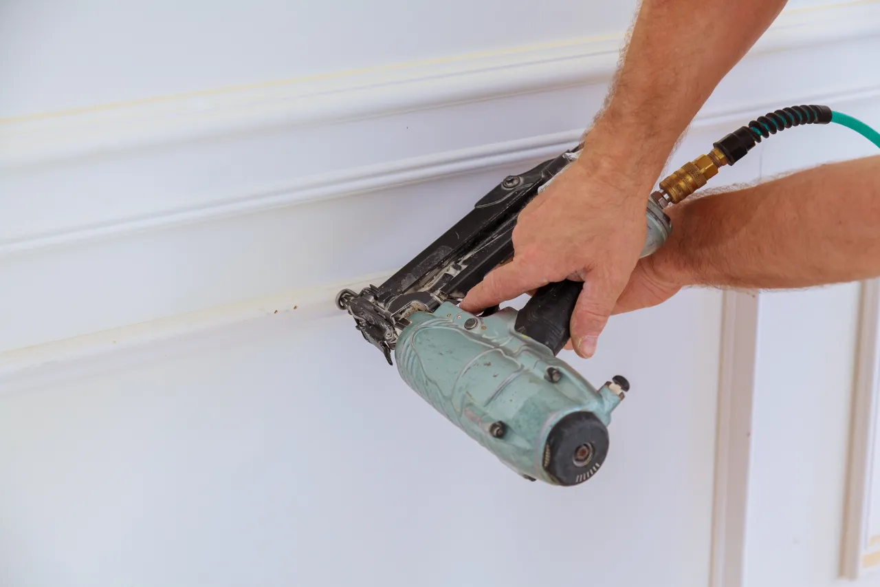 Worker using nail gun on white trim molding in New Jersey